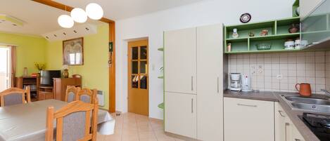 Una cocina con zona de comedor, con una mesa y sillas, una cafetera y un lavabo.