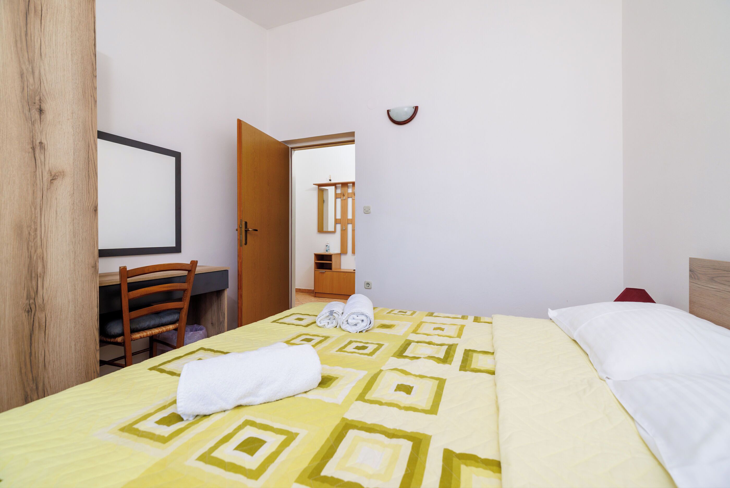 Une chambre d’hôtel avec un lit, un bureau, une chaise et un miroir.