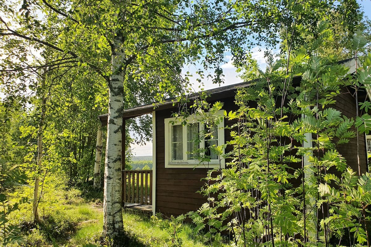 A wooden cabin surrounded by lush greenery and trees.