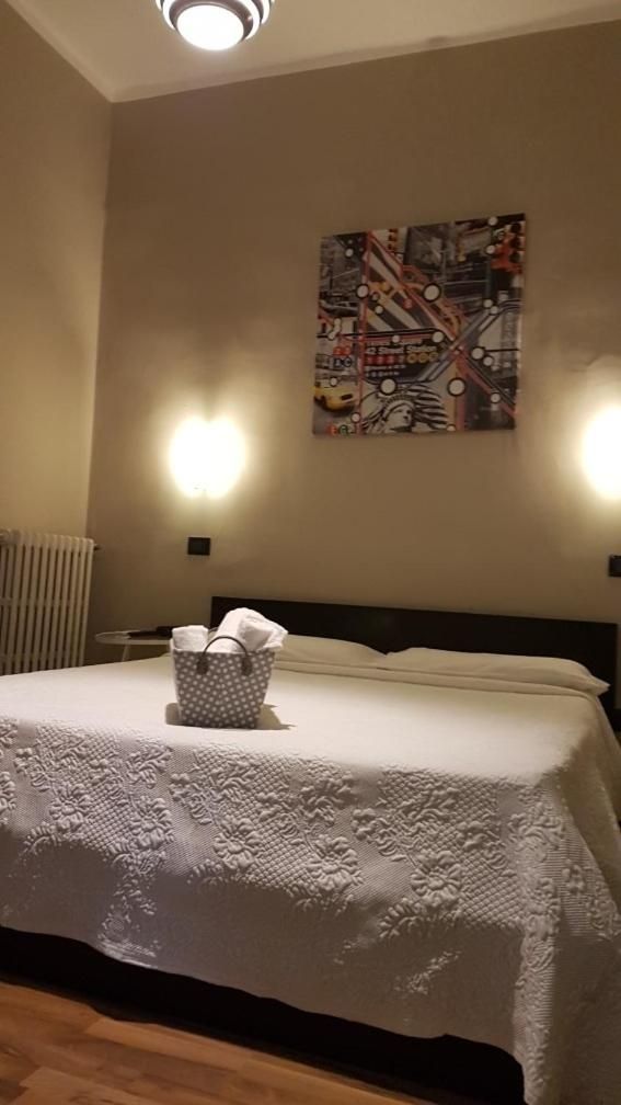 Une chambre d’hôtel avec un lit, une œuvre d’art accrochée au mur et deux appliques murales.
