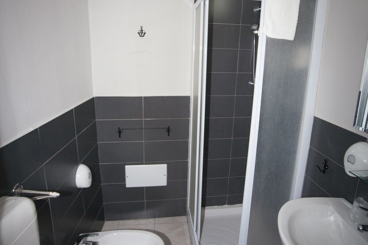 A bathroom with a toilet, bidet, sink, and a glass-enclosed shower.