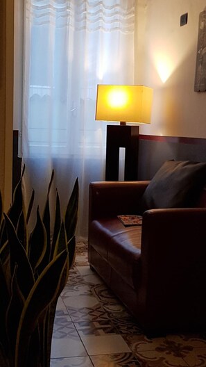 A living room with a sofa, a lamp, and a plant. - Albergo La Svolta (Brescia)