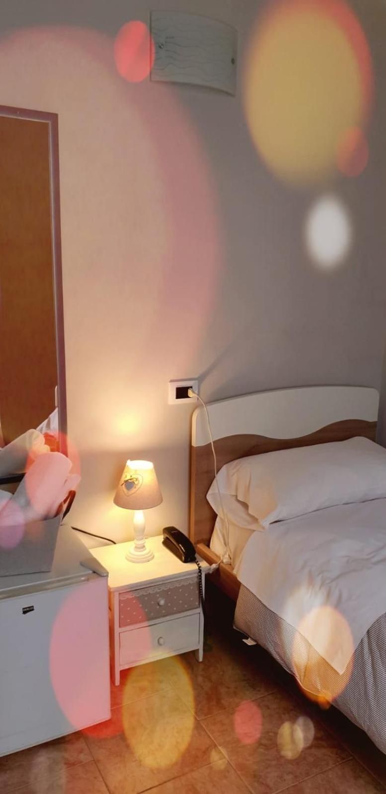 Ein Schlafzimmer mit einem Bett, einem Nachttisch, einer Lampe und einer Wand-Klimaanlage.