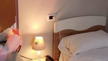 Ein Schlafzimmer mit einem Bett, einem Nachttisch, einer Lampe und einer Wand-Klimaanlage.