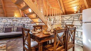 A wooden dining table with chairs, a stone wall, and a staircase. - Theasis Igloo (Central Tzoumerka)