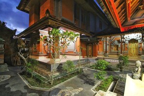 A traditional building with a covered courtyard, stone steps, and a statue. - Happy Inn (Ubud)