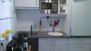 A compact kitchen with a microwave, toaster, coffee maker, and a sink. - FeWo Paula (Oberstaufen)