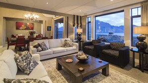 A spacious living room with a large window offering a mountain view, a dining area with red chairs, and a chandelier.