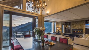 A spacious dining area with a large table, red upholstered chairs, and a view of the mountains through large windows.