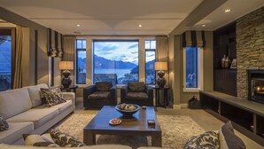 A modern living room with a sofa, armchairs, a coffee table, and a fireplace.