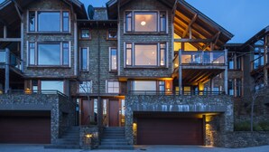 A multi-story house with a stone facade, large windows, and a garage.