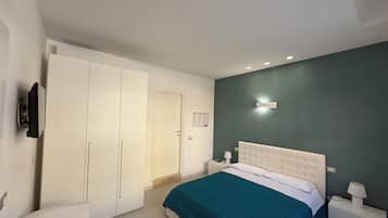 A bedroom with a bed, a wardrobe, a nightstand, and a TV.