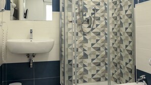 A bathroom with a glass-enclosed shower, a sink, and a bidet. - The Smerald (Alghero)
