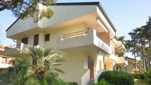 A two-story residential building with balconies, surrounded by greenery and trees. - Appartamenti dei Fiori (Lignano Sabbiadoro)