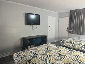 Une chambre d’hôtel avec deux lits, un bureau, une télévision et une porte.