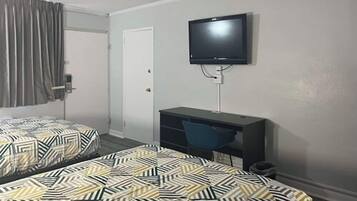 Habitación de hotel con dos camas, un escritorio, una silla y un televisor instalado en la pared.