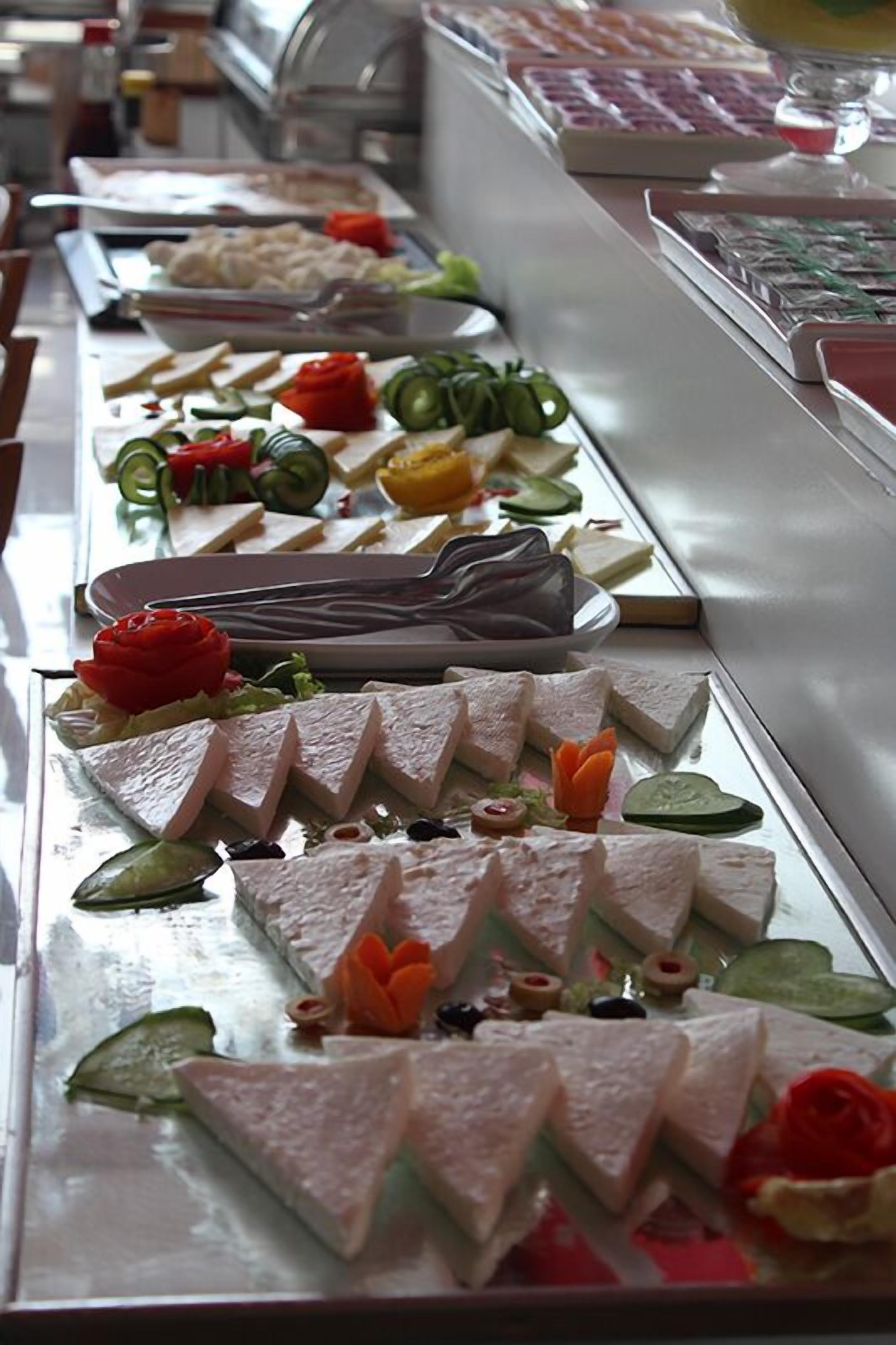 Een buffet met diverse gerechten, waaronder vleesschotels, groenten en garneringen.