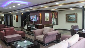 Eine Hotelhalle mit Sofas, einem Couchtisch, einem Fernseher und einer Treppe.