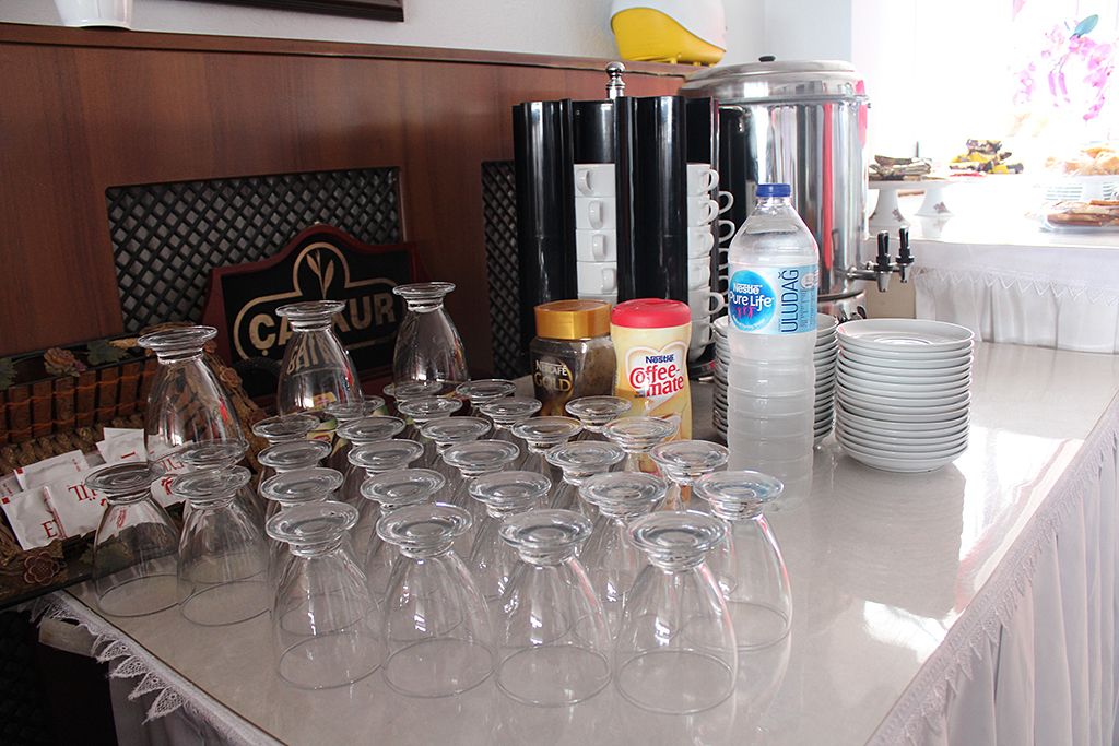 A buffet setup with clear glassware, condiment bottles, and a water dispenser.