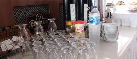 A buffet setup with clear glassware, condiment bottles, and a water dispenser.