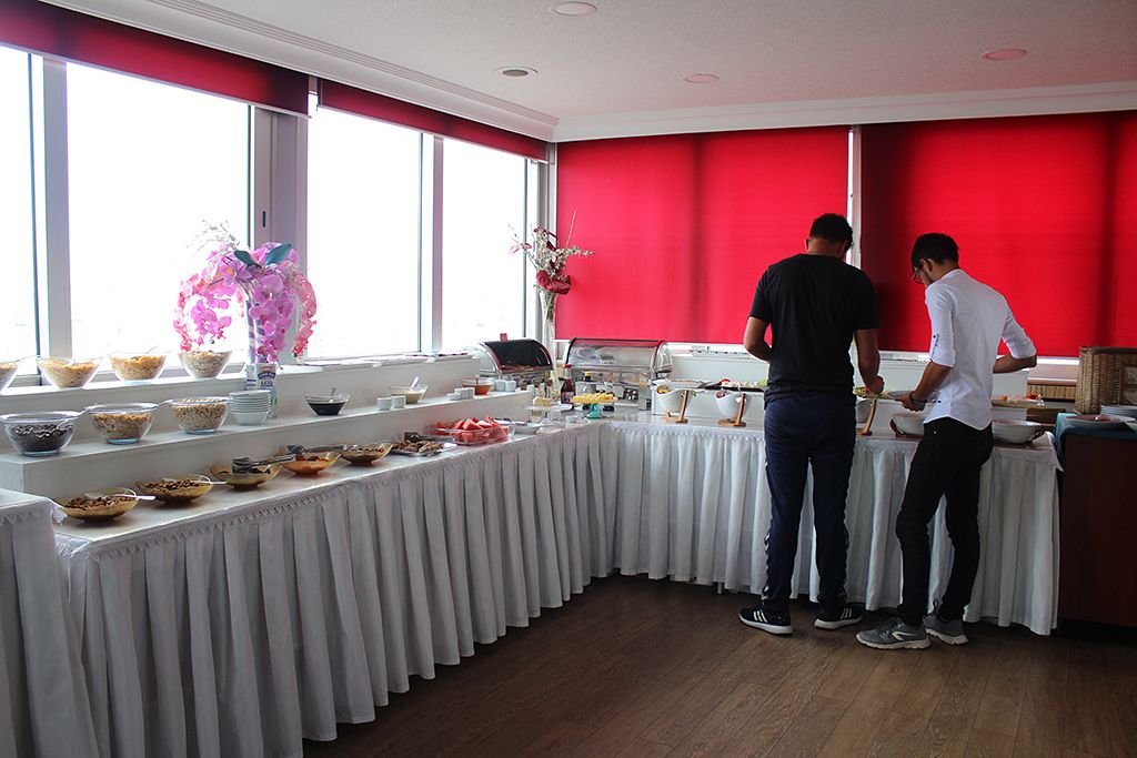 A buffet setup with various food items and a decorative pink orchid arrangement.