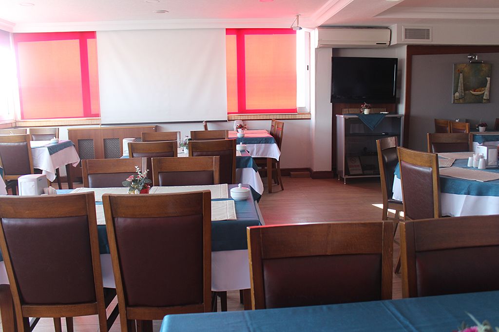A dining area with multiple tables and chairs, a television, and a painting on the wall.