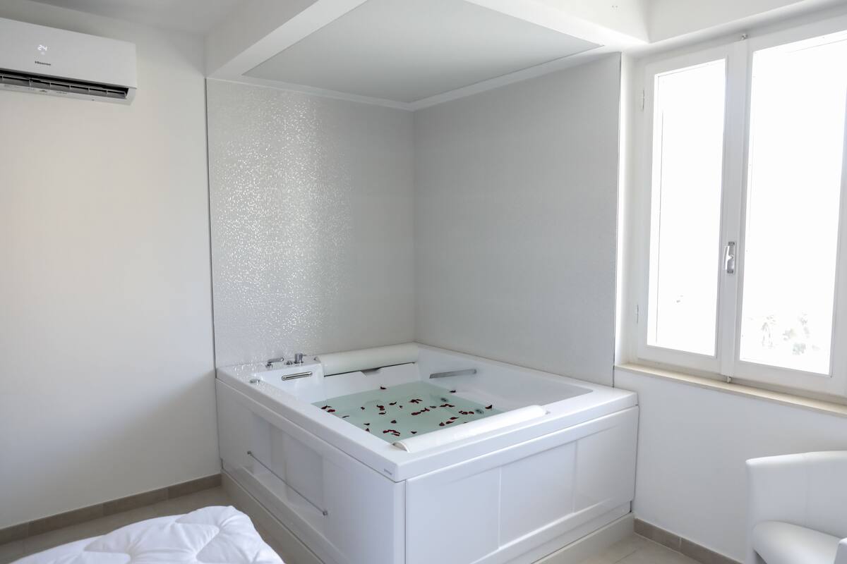 A modern bathroom with a freestanding bathtub, a large mirror, and a window providing natural light.