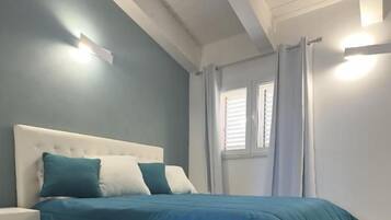 Een slaapkamer met een bed, nachtkastje en een raam met gordijnen.