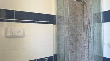 Une salle de bain avec une douche à parois de verre, des toilettes et un bidet.