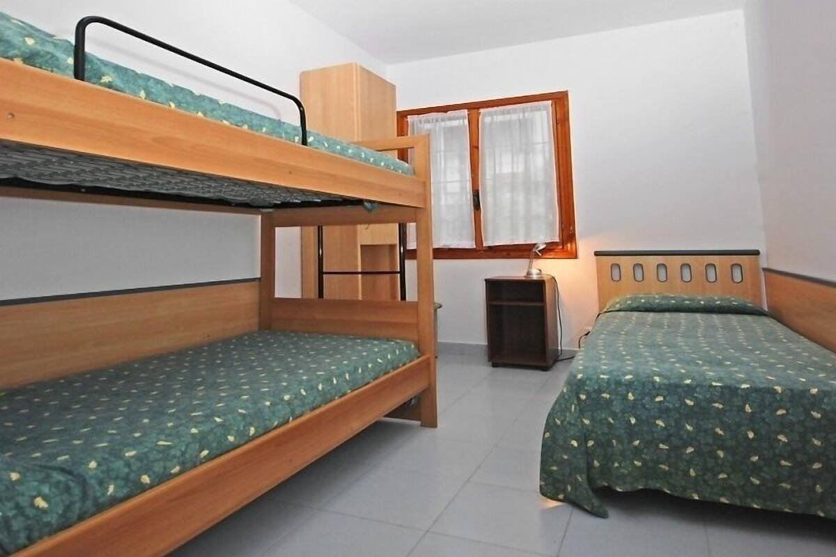 Een kamer met stapelbedden, een kleine tafel en een raam met gordijnen.