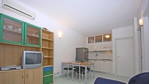 Un espacio habitable compacto con kitchenette, zona de comedor y área de estar con sofá.