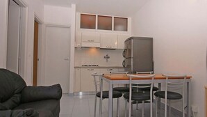 Un espacio habitable compacto con kitchenette, comedor y televisor.