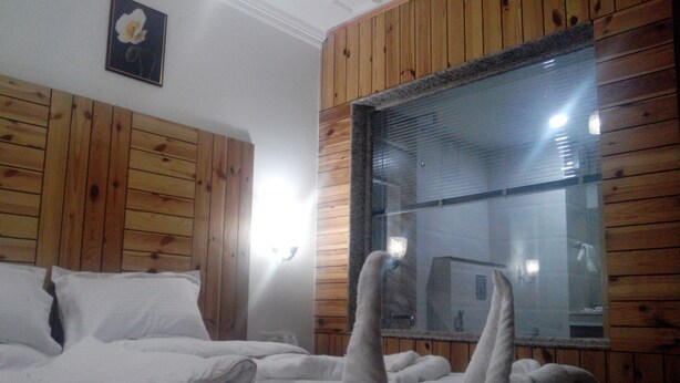 Un dormitorio con paneles de madera, un ventanal grande y una cama con ropa de cama blanca.