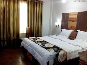 Enjoy a restful stay in this executive room with a comfortable bed, bedside table, and chair.