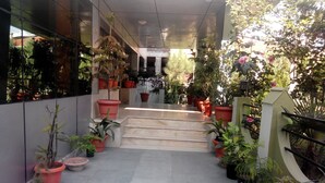 Un paseo techado con plantas en macetas y escaleras que conducen a la entrada de un edificio.