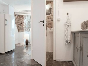 A hallway with a white door leading to a room with a stone wall and a sink. - Loft unter Tage Essen Rüttenscheid (Essen)
