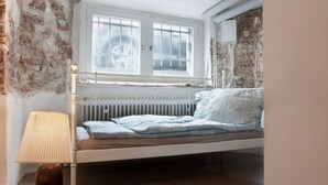 Un dormitorio con cama, radiador, ventana y lámpara.
