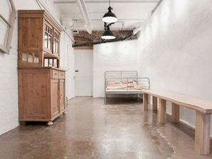 A room with a wooden cabinet, a metal bed frame, and a bench. - Loft unter Tage Essen Rüttenscheid (Essen)