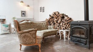 Una sala de estar con un sofá antiguo, una chimenea y una pila de leña.