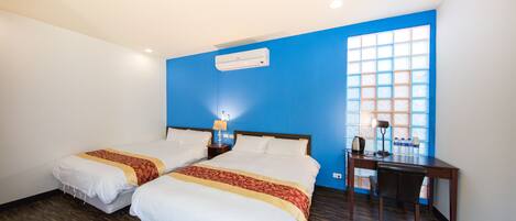 Habitación de hotel con dos camas, un escritorio y ventana con pared azul y vistas.
