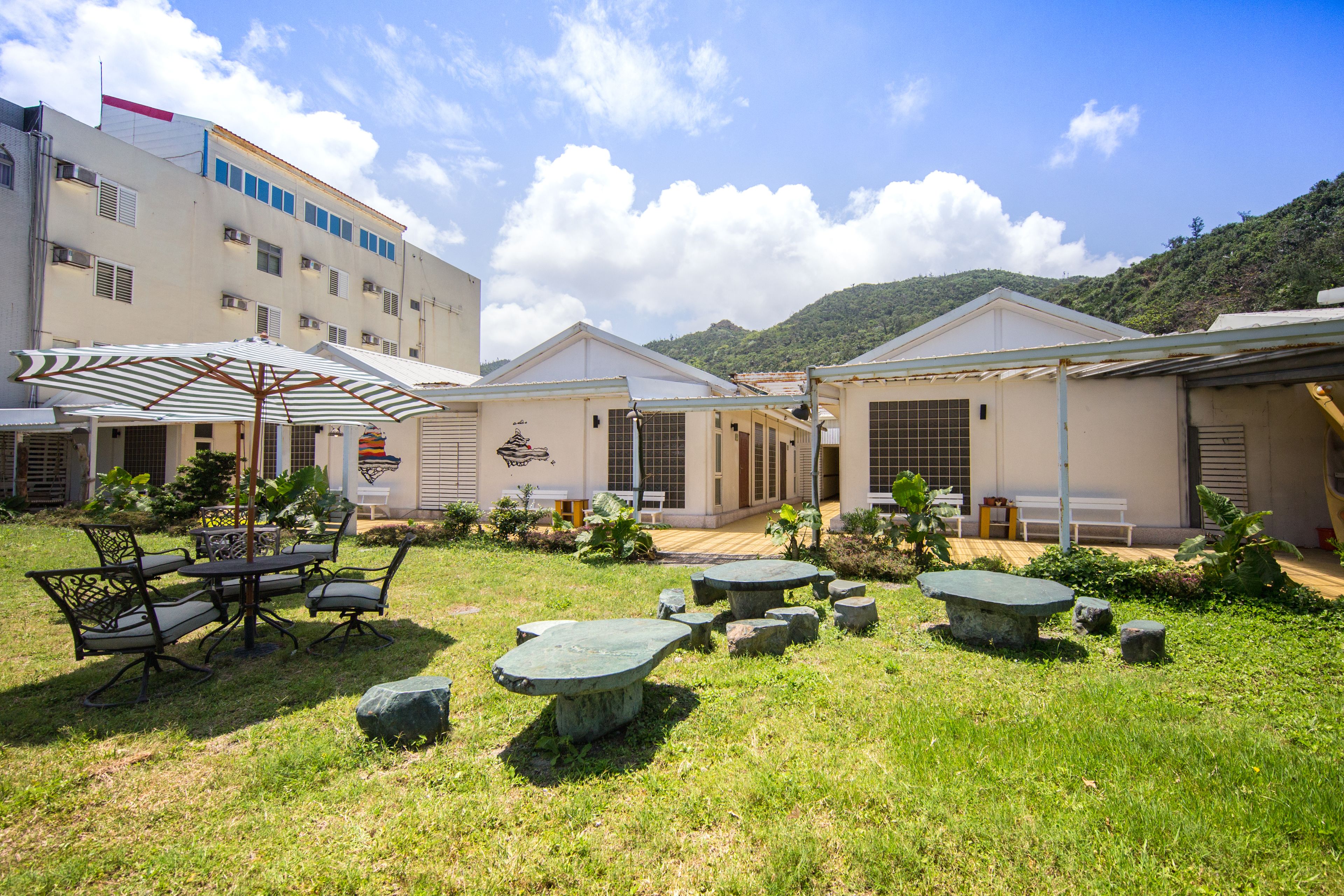 A courtyard with outdoor seating, a building with multiple windows, and a mountain in the background.