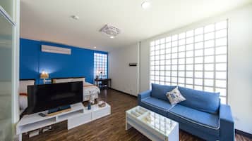 Habitación cuádruple Deluxe | Área de sala de estar | Televisión de pantalla plana