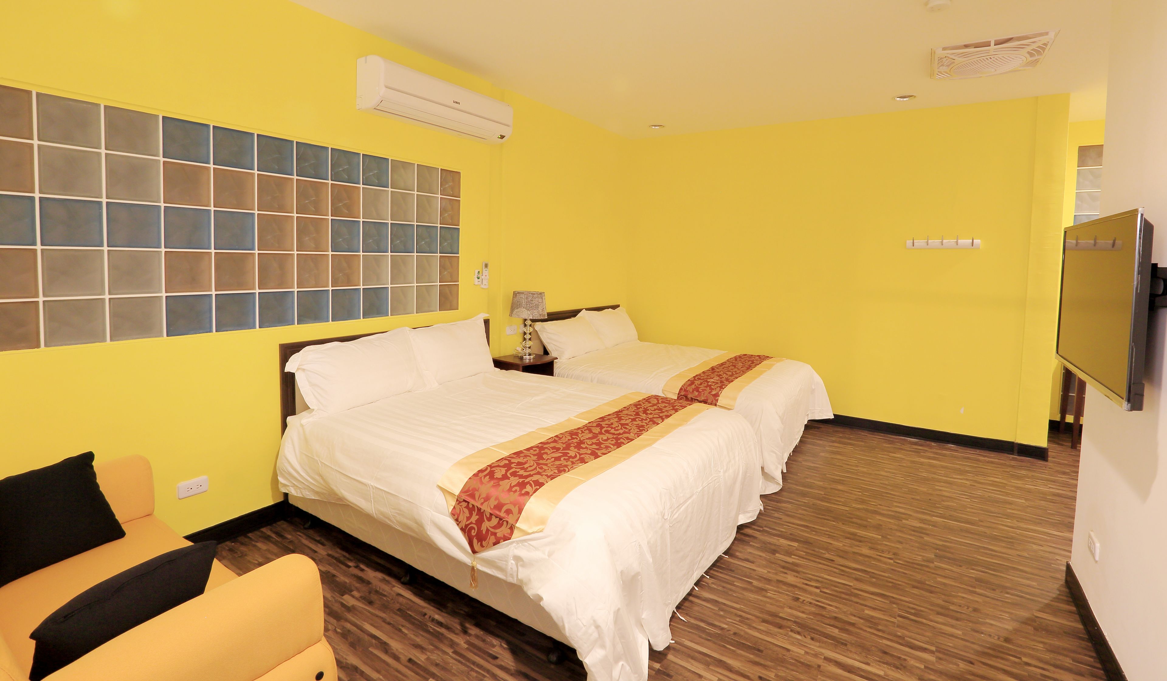 Habitación de hotel con dos camas, suelo de madera, un ventanal con vistas y un televisor en la pared.