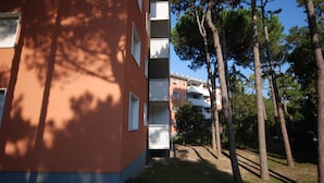 Un immeuble à plusieurs étages doté de balcons, entouré d’arbres et d’une zone herbeuse.