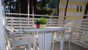 Une terrasse extérieure blanche, avec une table et deux chaises, entourée d’une clôture blanche.