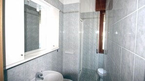 Casa de banho com lavatório, espelho e sanita.