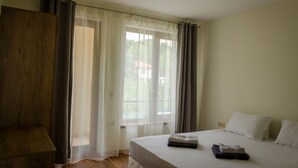 A room with a bed, a wooden wardrobe, and a window with sheer curtains. - Sunny Suites by Casa Del Mare (Varna)