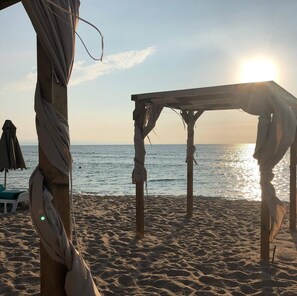 A beach scene with a wooden structure, possibly a beach chair or small table, and a beach umbrella in the background. - Sunny Suites by Casa Del Mare (Varna)