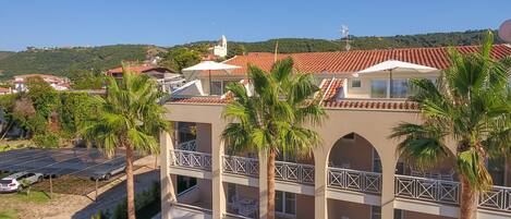 A multi-story hotel with balconies, palm trees, and a view of the surrounding area.