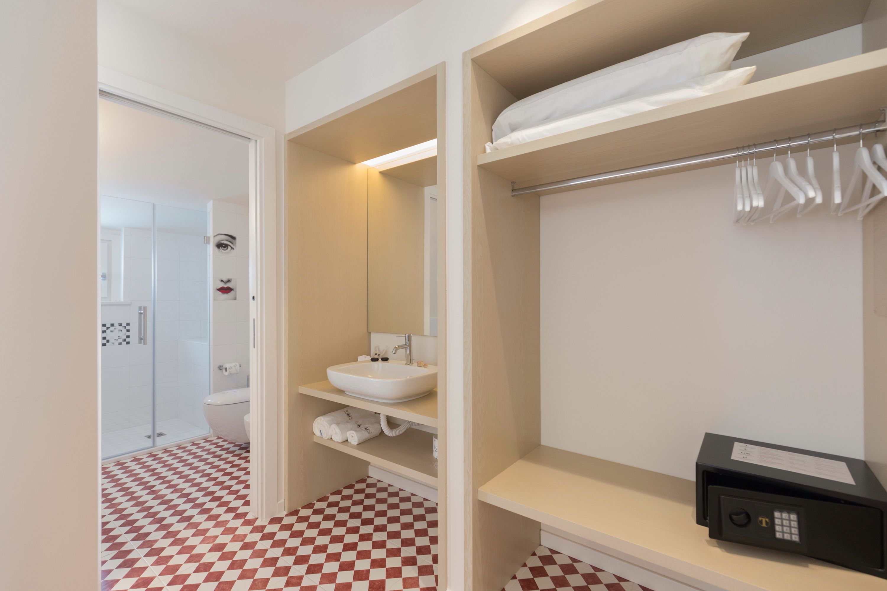 Un baño moderno con piso a cuadros, un lavamanos blanco, un espejo y un perchero para toallas.